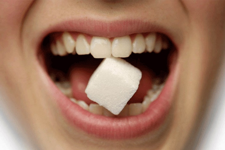 Кусочек сахара зажат между зубами